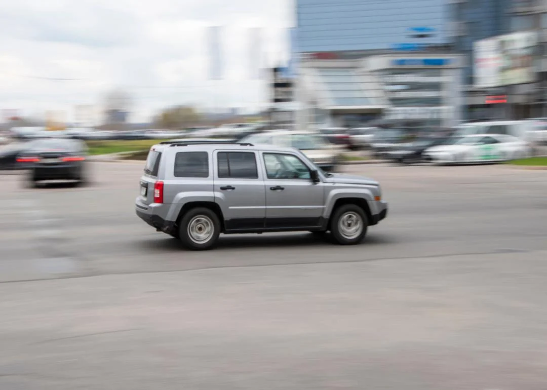 a silver jeep patriot speeding down the road.