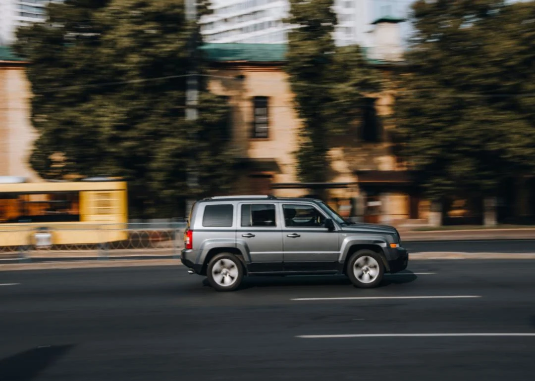 a gray jeep patriot speeding down a highway.