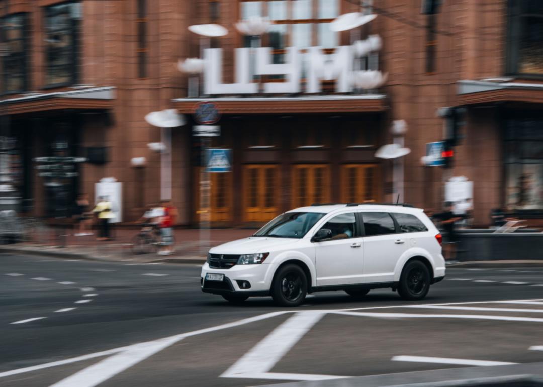 a white dodge journey speeding through a city.