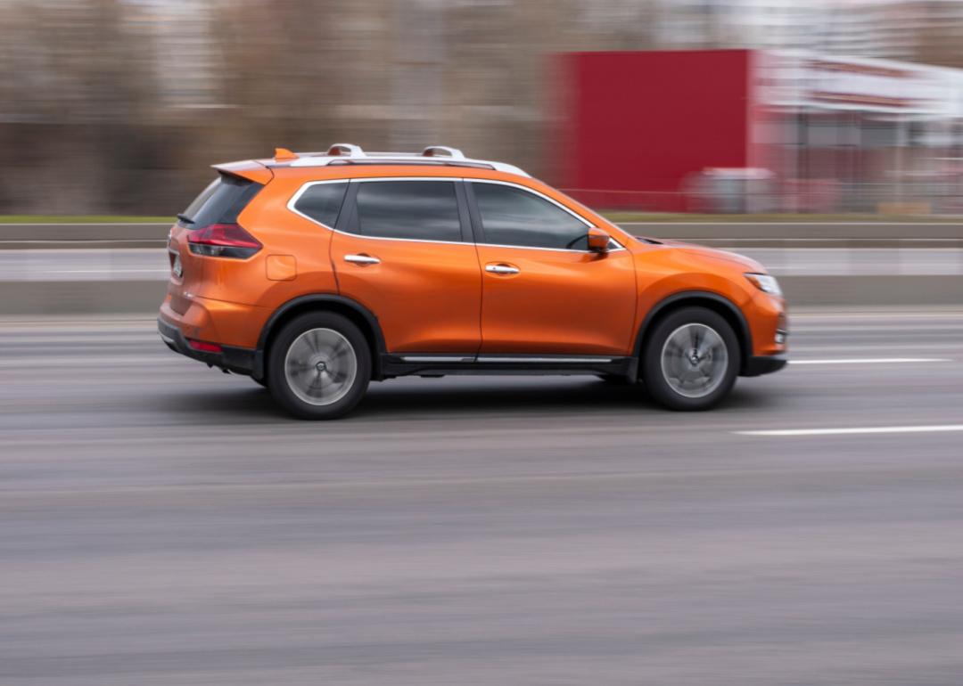 an orange nissan rogue speeding down the road.