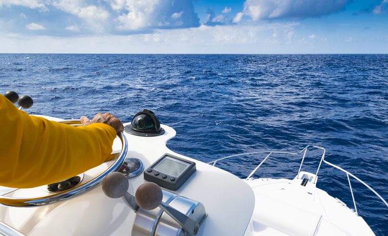 hand of captain on steering wheel of motor boat in the blue ocean